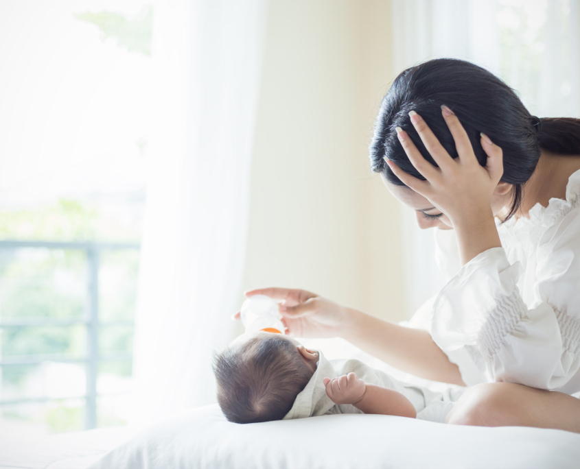 Mutter stütz sich ab während sie ihr Baby füttert